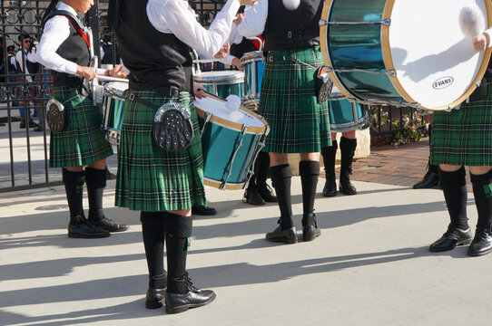 Green tartan kilts and black socks, flashes and brogues of a Highland Pipe Band drum core practising before competing in a national competition.