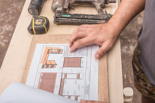 A man reviews the working drawings of a computer desk to be built at a furniture workshop.