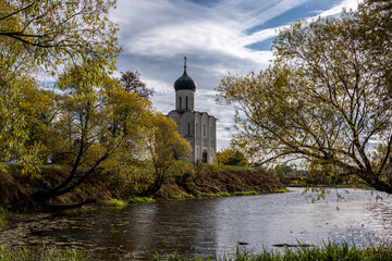 Obraz premium white-stone church in the field against the backdrop of autumn nature