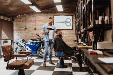 Young adult hairdresser with a client at work smiling