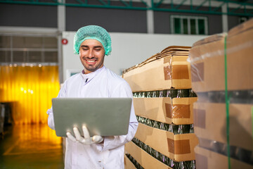 worker with laptop is checking product on the production line in the beverage factory. Manufacturer checks quality of food industry.