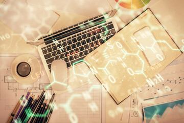 Physics and math theme hologram with formula drawings over computer on the desktop background. Top...