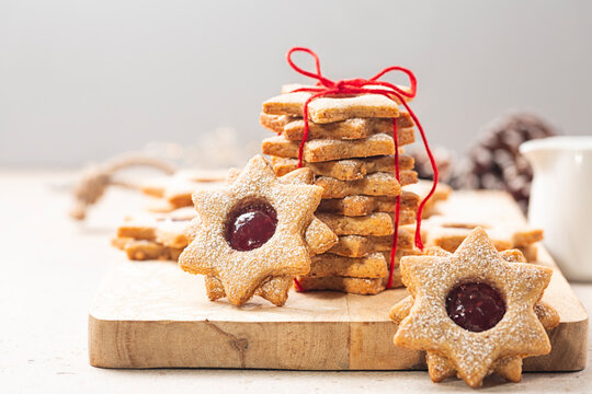 Cookie gift. Homemade star or flower shaped linzer cookies with raspberry jam, tied with red ribbon. Christmas or mother day present concept. Selective focus. Copy space.