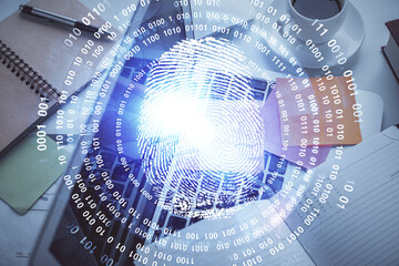 Finger print over computer on the desktop background. Top view. Double exposure. Concept of securitization.