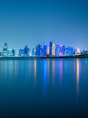 Fototapeta premium Vertical long exposure shot of Doha city skylines illuminated at night in Doha, Qatar