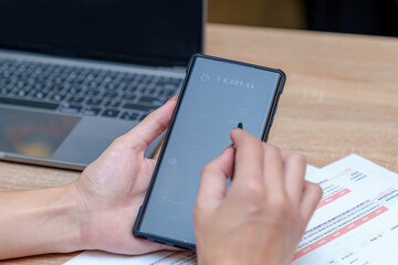 A businesswoman is transferring money using a financial app in her office.