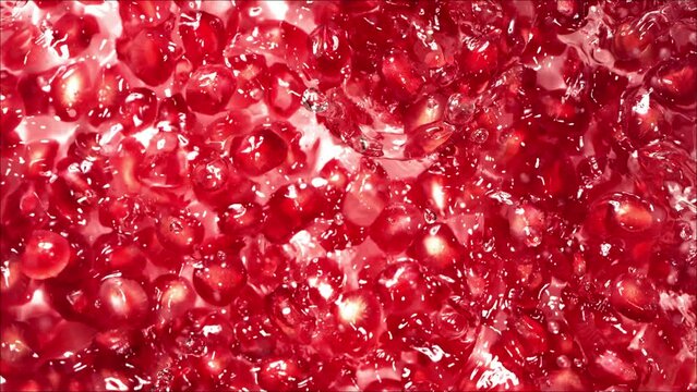 Pomegranate seeds falling on water surface with pomegranate seeds. 4K. Slow Motion.