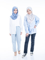 Portrait of two beautiful Muslim young women wearing modern and stylish casual wear with hijab isolated from studio background. Modern hijab fashion and beauty concept