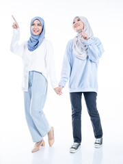 Portrait of two beautiful Muslim young women wearing modern and stylish casual wear with hijab isolated from studio background. Modern hijab fashion and beauty concept