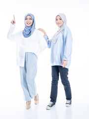 Portrait of two beautiful Muslim young women wearing modern and stylish casual wear with hijab isolated from studio background. Modern hijab fashion and beauty concept