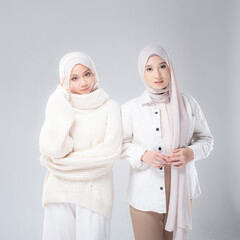 Portrait of two beautiful Muslim young women wearing modern and stylish casual wear with hijab isolated from studio background. Modern hijab fashion and beauty concept