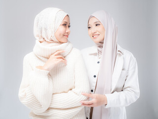 Portrait of two beautiful Muslim young women wearing modern and stylish casual wear with hijab isolated from studio background. Modern hijab fashion and beauty concept