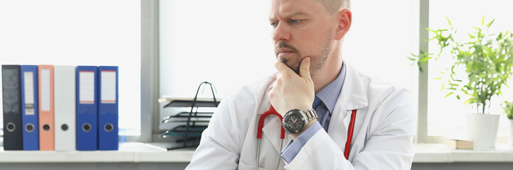 Middle aged medical worker in white uniform confused look in laptop screen