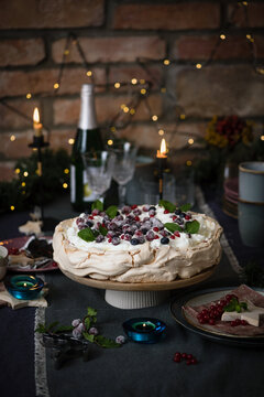 Christmas cake Pavlova with berries decorated on dark blue background with Christmas decoration