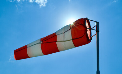 Windsock. Windsock flag. Wind direction indicator. Wind intensity. Windsock in front of blue sky.