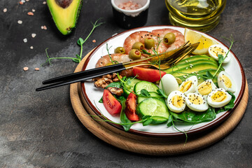 Ketogenic breakfast. Keto low carb shrimps, prawns, quail eggs, fresh salad, tomatoes, cucumbers and avocado on a dark background. keto diet. Top view