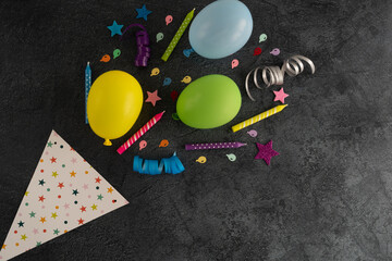 Happy Birthday composition, with colorful balloons, cake candles, streamers, bows and ribbons. Birthday party invitation, decorations explosion. Top view flat lay concept, with copy space.