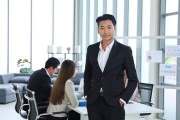 Portrait of smart Asian businessman standing with business people meeting and talking in the room background