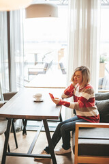 Relaxed woman with mobile in the indoor cafe