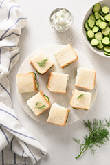 Cucumber sandwiches with ricotta and dill on white background. Top view. Vertical format
