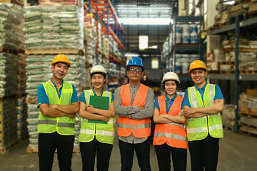 Group of warehouse workers in hardhat and reflective jacket standing with arm crossed and looking...