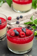 Delicious italian dessert panna cotta with berry sauce on a dark background in small jars. place for text