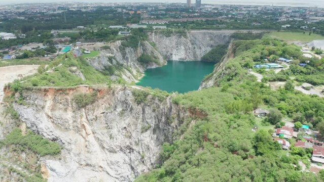 Grand Canyon Chonburi. Trucks dig coal mining of ore with black grunge ground in quarry with mountain hills. Nature landscape background in factory industry. Environment. Aerial footage b roll 4k.