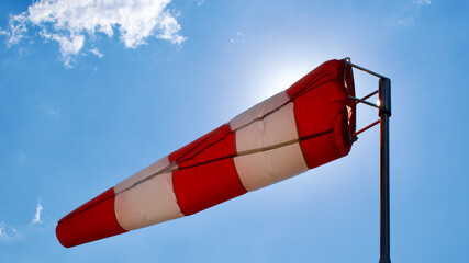 Windsock. Windsock flag. Wind direction indicator. Wind intensity. Windsock in front of blue sky.