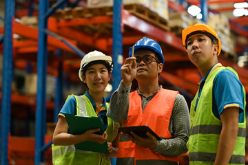 Senior male manager and young workers discussing work and checking stock, order details on digital tablet