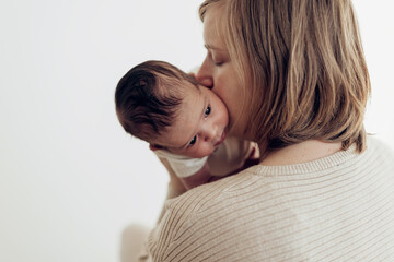 mom hugging and kissing her toddler on white background
