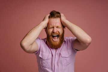 Adult stressed redhead bearded man holding head and shouting