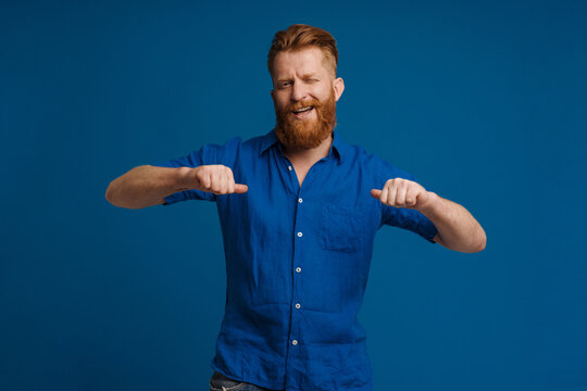 Adult handsome stylish redhead bearded smiling man poitning on himself