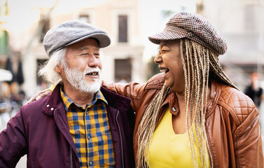 Happy multiracial senior couple having fun in city - Elderly people and love relationship concept