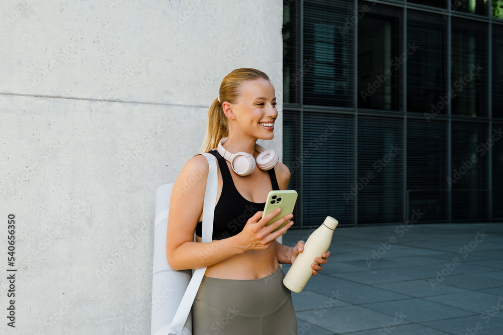 Wall mural White young woman using mobile phone after yoga practice