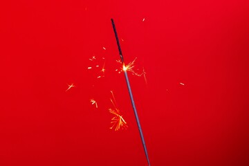 Close-up of a flaming sparkler on a red background. New Year's concept, holiday