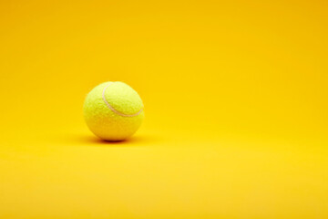 Extreme close up tennis ball isolated on the bright solid fond plain yellow background. Sport inventory and equipment concept