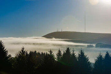 Winter Hill on a misty Autumn Fall morning with mist in the valley lens flare and copy space