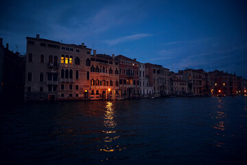 Fototapeta na wymiar Venice deep evening night landscape with the view of venetian houses with luminous windows on the Grand canal