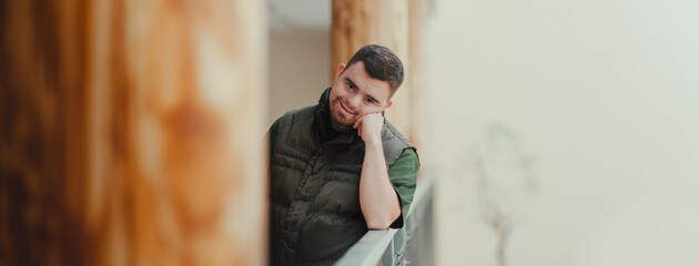 Portrait of young pensive man with down syndrome, resting after cleaning animal enclosure in zoo....