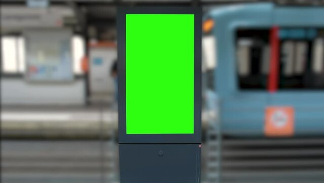 Close-up of the Green Screen High Street billboard. Blank information banner in the style of a chromatic key against the background of a blurred monorail streetcar.