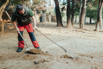 Caretaker with down syndrome in zoo cleaning animal enclosure. Concept of integration people with disabilities into society.