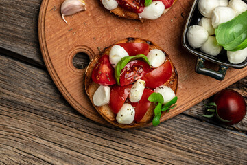 Open sandwiches with cherry tomatoes, mini mozzarella, fresh basil leaves, caprese on bread, Traditional italian appetizer or snack, antipasto. banner, menu, recipe place for text, top view