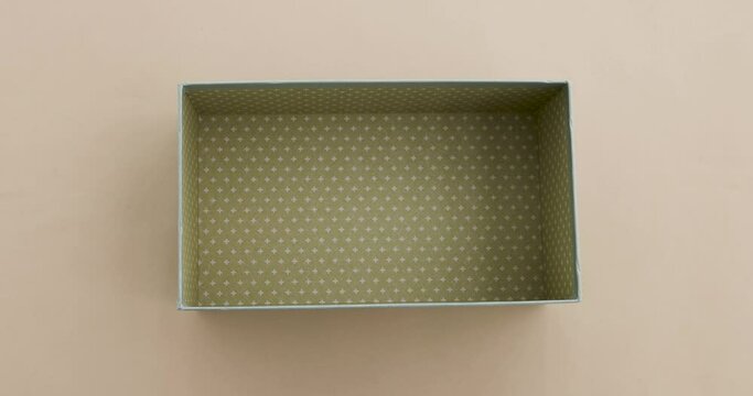 Female hands open a silver gray light box with a bow and you can see empty package beige delicate background top view. Female hands close and take away an empty gift box