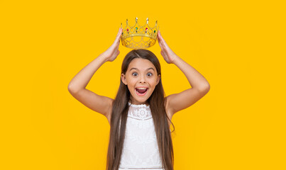 amazed teen girl in crown on yellow background