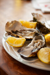 Fresh oysters close-up on a white plate, served table with lemon. Healthy sea food. Dinner of fresh oysters in a restaurant. Selective focus with shallow depth of field.
