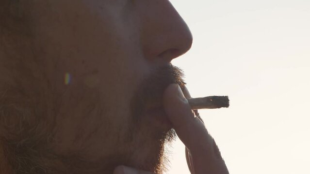 Man smoking marijuana, weed, joint, getting high, sunshine, smoke. 4K 24FPS.