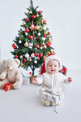 Santa baby. Christmas tree background. Happy New Year! Child in Santa's hat.