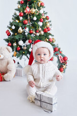 Obraz na płótnie Canvas Santa baby. Christmas tree background. Happy New Year! Child in Santa's hat.