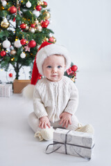 Obraz na płótnie Canvas Santa baby. Christmas tree background. Happy New Year! Child in Santa's hat.