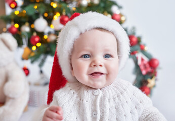 Santa baby. Christmas tree background. Happy New Year! Child in Santa's hat.